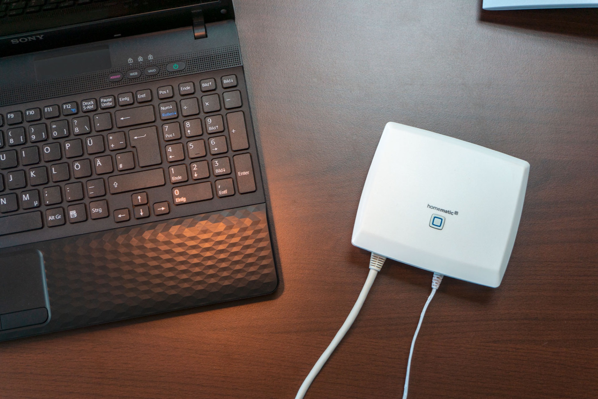 Netzwerkzugangspunkt von Homematic IP neben einem Notebook